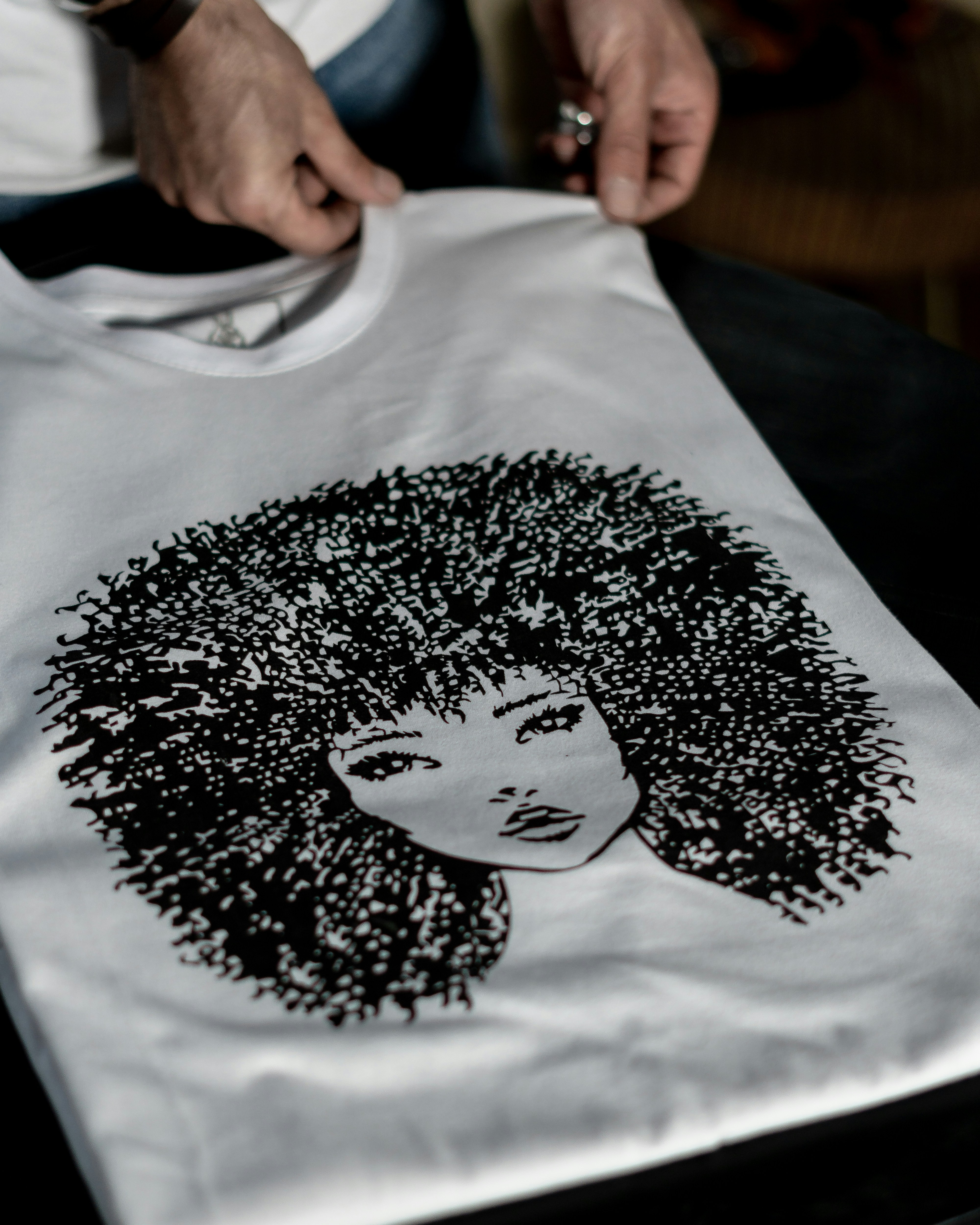 Detailed and Fine screen print of black woman with an afro on a white shirt on a screen printing press.