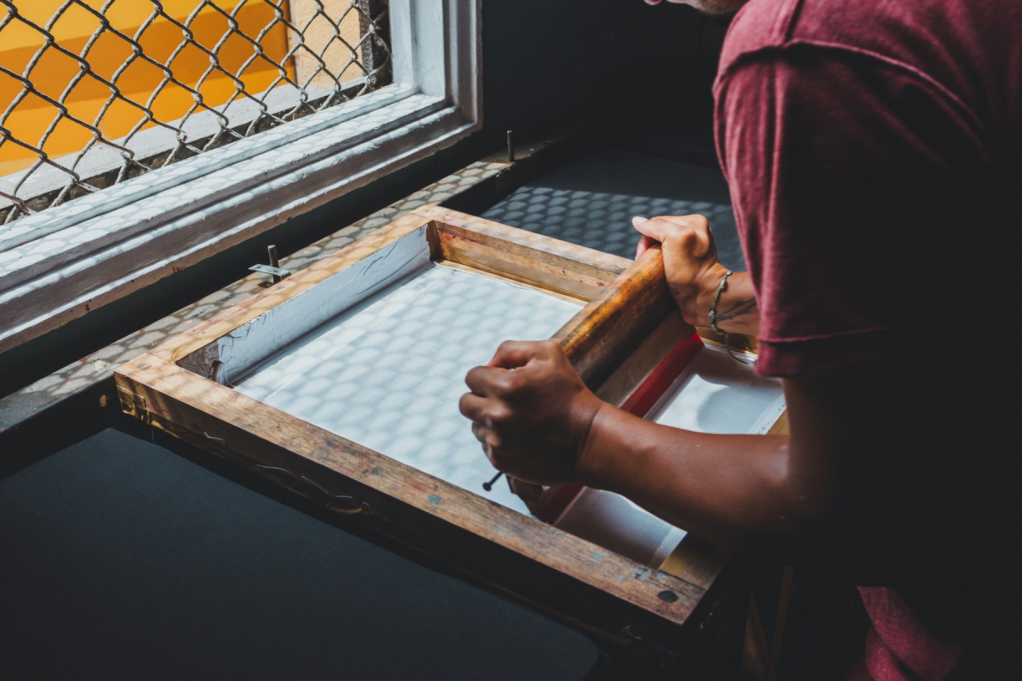 Hands pulling a screen for a custom apparel print